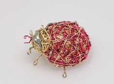 a ball of yarn and some metal hooks on a white surface with a red string attached to it