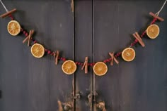 orange slices and cinnamon sticks are hanging from a string on a wooden door with wine corks