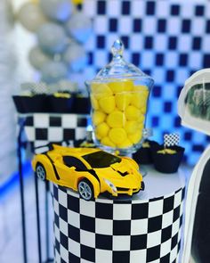 a yellow toy car sitting on top of a table next to a vase filled with yellow candies