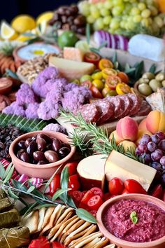 an assortment of fruits and vegetables on a platter with cheese, crackers, grapes, nuts, breadsticks