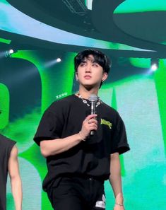 two young men standing next to each other while holding microphones in their hands and wearing black shirts