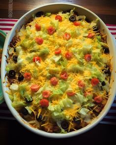 a large casserole dish with cheese, lettuce and tomatoes in it