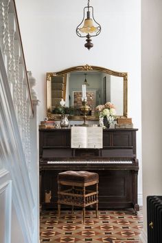 a piano sitting in front of a mirror on top of a wooden table next to a stair case