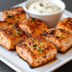 grilled salmon on a white plate with a small bowl of ranch dressing