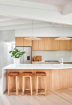 a kitchen with two stools next to an island and a potted plant on the counter