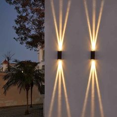 two wall lights on the side of a building with palm trees in front of them