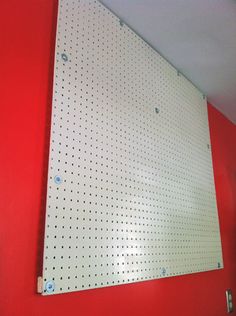 a metal pegboard mounted to the side of a red wall