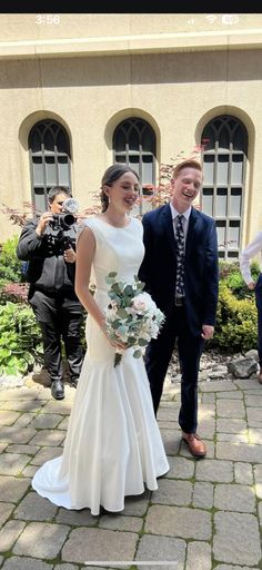 a man and woman standing next to each other in front of a building with cameras