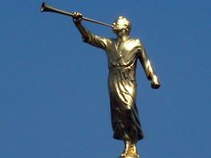 a golden statue holding a baseball bat on top of a tall building with a blue sky in the background