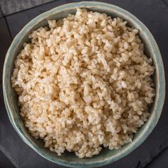 a bowl filled with brown rice sitting on top of a black tablecloth covered floor