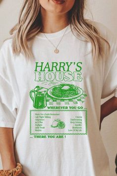 a woman wearing a harry's house t - shirt with her hands in her pockets