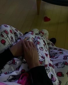 a person laying on top of a bed covered in hello kitty pajamas and holding onto the pillow