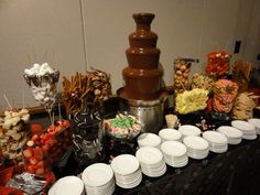 an assortment of candy and candies on a table with chocolate fountain in the background