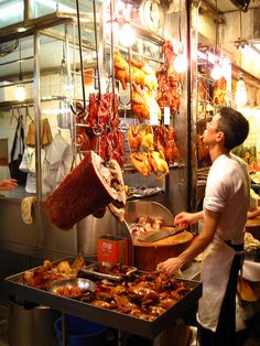 a man standing in front of a counter filled with meats and other food items