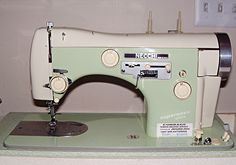 an old sewing machine sitting on top of a green table next to a white wall