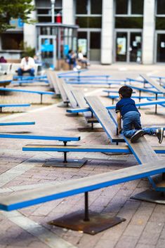 a small child sitting on top of blue benches