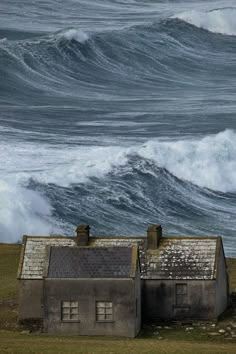 an old house sitting in front of a large wave