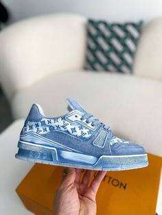 Step into iconic style with these LV Trainer-inspired sneakers reimagined in cool blue monogram denim. This contemporary take on a classic silhouette blends casual comfort with high-fashion appeal. The signature Louis Vuitton monogram adds a touch of understated luxury, while the clean lines and chunky sole create a versatile look that's perfect for everyday wear. Your order arrives in a branded shoe box, complete with dust bags, extra laces, socks, a care booklet, and a branded key holder. Blue Sneakers With Embossed Logo For Streetwear, Blue Casual Sneakers With Embossed Logo, Trendy Denim Sneakers For Streetwear, Trendy Denim Blue Sneakers For Streetwear, Designer Blue Low-top Custom Sneakers, Luxury Blue Sneakers For Streetwear, Designer Blue Sneakers For Spring, Fall Winter Jacket, Blue Trainers