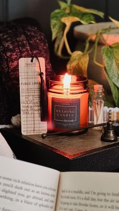 a candle sitting on top of a table next to an open book and some candles