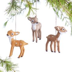 three deer ornaments hanging from a pine tree