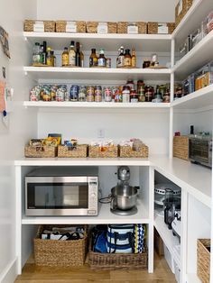 an organized pantry with white shelves and baskets