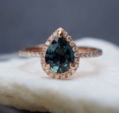 a close up of a ring on top of a white rock with a green stone in the middle