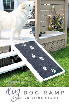 a white dog standing on top of a ramp next to a wooden structure with paw prints