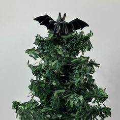 a fake bat sitting on top of a green plant