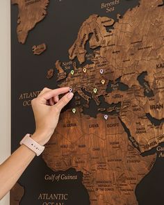 a person pointing at a map on the wall with pins pinned to it's sides