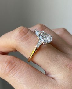 a woman's hand with a diamond ring on top of her finger and an engagement band