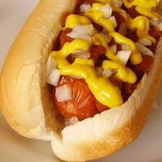 a hot dog covered in mustard and onions