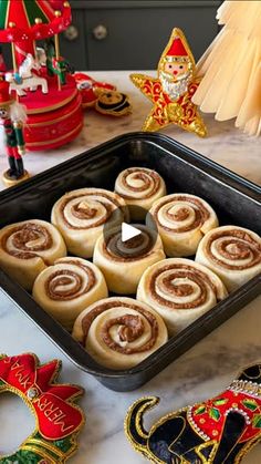 a pan filled with cinnamon rolls sitting on top of a counter next to christmas decorations