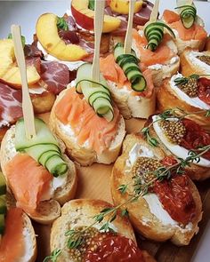 an assortment of finger foods are displayed on a cutting board with toothpicks in them