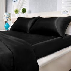 a bed with black sheets and pillows on it