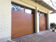 two wooden garage doors on the side of a house