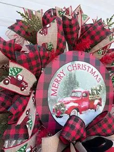 a christmas wreath with an old red truck and plaid ribbon on the front of it