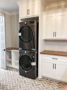 a washer and dryer sitting in a room with white cupboards on the wall