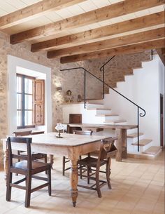 a dining room table and chairs in front of a staircase leading up to the second floor