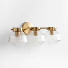 three glass globe lights are mounted on the wall in an elegant style with gold accents