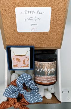 an open gift box containing a jar of candles and a blue polka dot bow tie