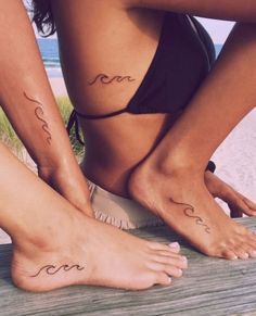 two women with matching tattoos on their feet are standing next to each other near the beach