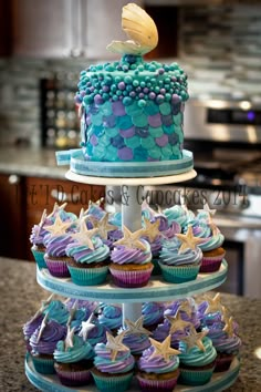 three tiered cake with cupcakes on it