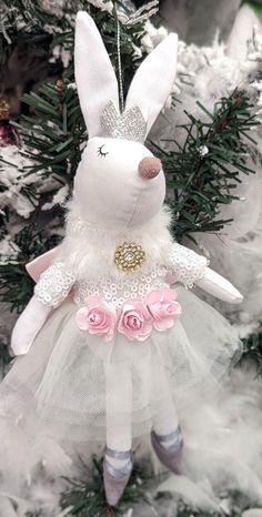 a white stuffed animal with pink roses on it's head hanging from a christmas tree