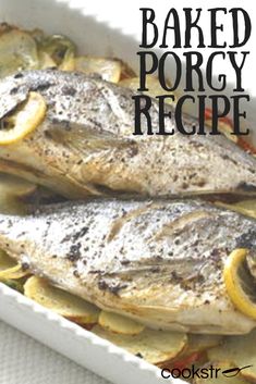 baked porgy fish with lemons and potatoes in a white dish on a table