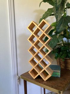 a wooden book shelf sitting on top of a table next to a potted plant