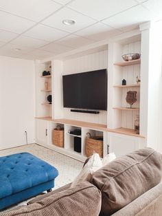 a large flat screen tv mounted to the wall in a living room next to a blue couch