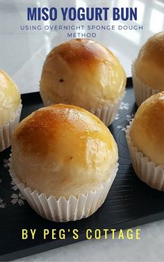 four muffins sitting on top of a black tray with white writing that reads misso yogurt bun using overnight space dough method