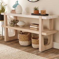 a wooden table with baskets and books on it in front of a wall mounted mirror