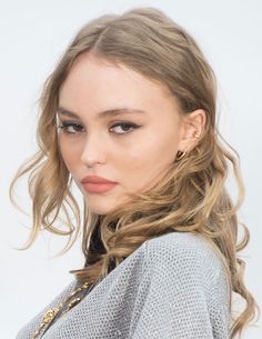 a close up of a person with long hair wearing a sweater and earrings on her head