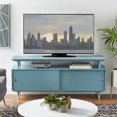 a living room with a large television on top of a blue entertainment center in front of a cityscape